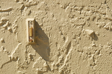 Image showing doorbell in stuccoed wall with shadow and copy space