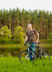 Image showing Young man on the GT bicycle biking through a sunny countryside. 