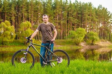 Image showing Young man on the GT bicycle biking through a sunny countryside. 