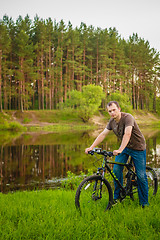 Image showing Young man on the GT bicycle biking through a sunny countryside. 