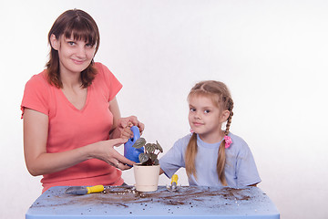 Image showing Mom and daughter watered transplanted flower room