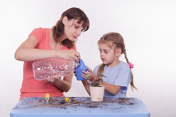 Image showing Mom and daughter poured water into a watering can flowers