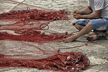 Image showing Fisherman repairs his net