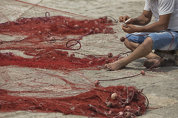 Image showing Fisherman repairs his net