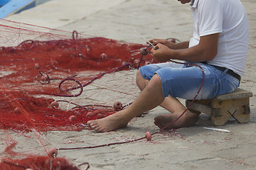 Image showing Fisherman repairs his net