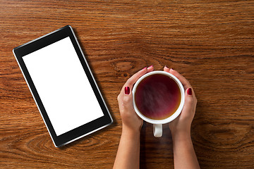 Image showing woman holding cup of tea with tablet pc on wood