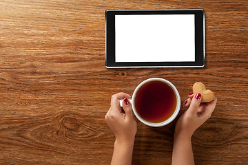 Image showing woman holding hot cup of tea with cookies