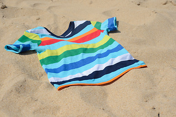 Image showing Multicolored child t-shirt on the sand