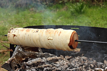 Image showing cooking kurtos kalacs on camp fire