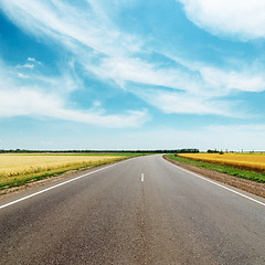 Image showing asphalt road to horizon between golden fields under blue sky wit