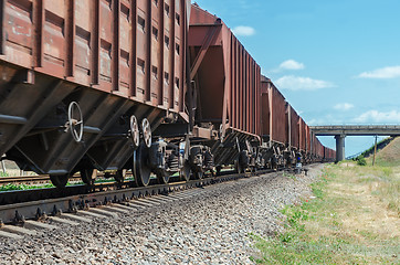 Image showing wagons of a freight train in motion go to horizon under bridge