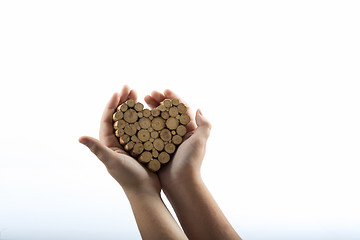 Image showing Young hands giving wooden heart