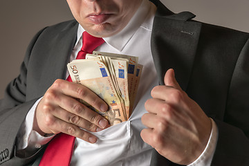 Image showing Businessman putting money in pocket