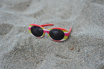 Image showing Children's striped sunglasses on the sand