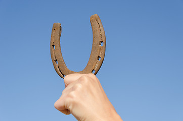 Image showing hand hold horseshoe symbol of luck on blue sky 