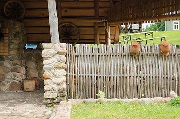 Image showing homestead house and wicker fence with old pots 