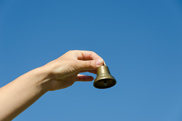 Image showing hand hold brass old jingle  on blue sky background 