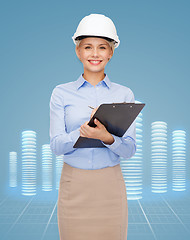 Image showing smiling businesswoman in helmet with clipboard