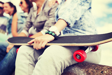 Image showing close up of female hand holding skateboard
