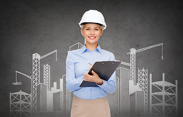 Image showing smiling businesswoman in helmet with clipboard