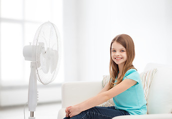 Image showing smiling little girl with big fan at home