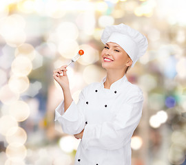 Image showing smiling female chef with fork and tomato