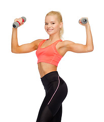 Image showing smiling beautiful sporty woman with dumbbells