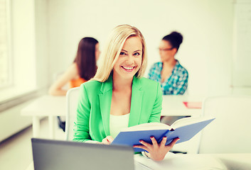 Image showing smiling young girl reading book at school