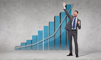 Image showing happy businessman with hands up near graph