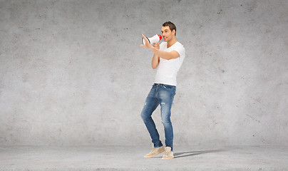 Image showing handsome man with megaphone over concrete wall