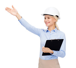 Image showing smiling businesswoman in helmet with clipboard