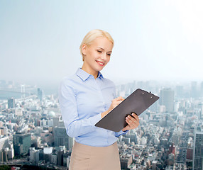 Image showing smiling businesswoman with clipboard and pen