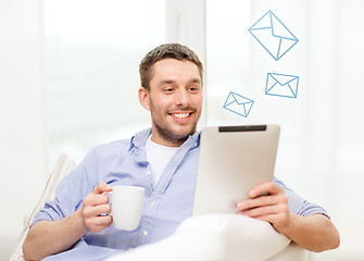 Image showing smiling man working with tablet pc at home