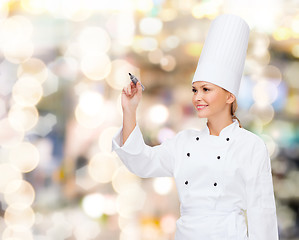 Image showing smiling female chef writing something on air