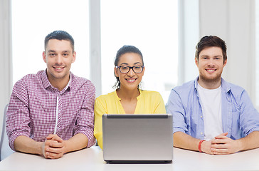 Image showing three smiling colleagues with laptop in office