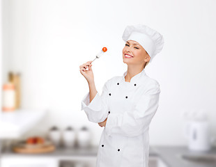 Image showing smiling female chef with fork and tomato