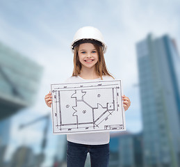 Image showing smiling little girl in helmet showing blueprint