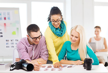 Image showing smiling team with printed photos working in office