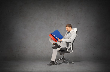 Image showing handsome businessman with folders sitting on chair