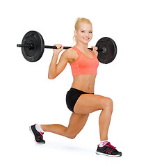 Image showing smiling sporty woman exercising with barbell