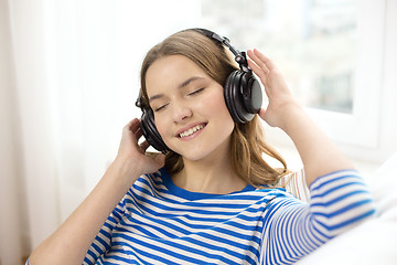 Image showing smiling young girl in headphones at home