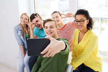 Image showing smiling students making picture with tablet pc