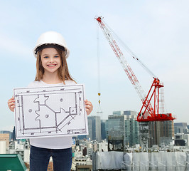 Image showing smiling little girl in helmet showing blueprint