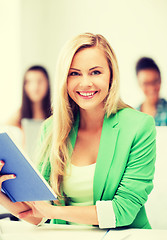 Image showing smiling young girl reading book at school