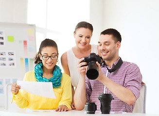 Image showing smiling team with photocamera working in office