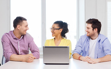 Image showing three smiling colleagues with laptop in office