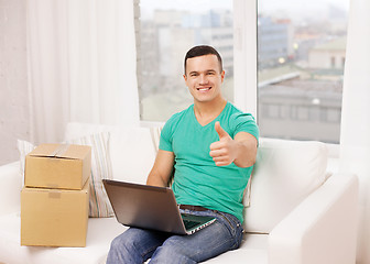 Image showing man with laptop and cardboard boxes at home