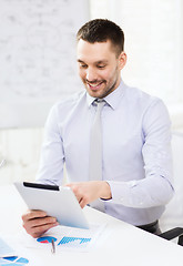 Image showing businessman with tablet pc and files in office