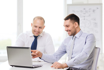 Image showing two smiling businessmen with laptop in office