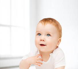 Image showing smiling baby lying on floor and looking up